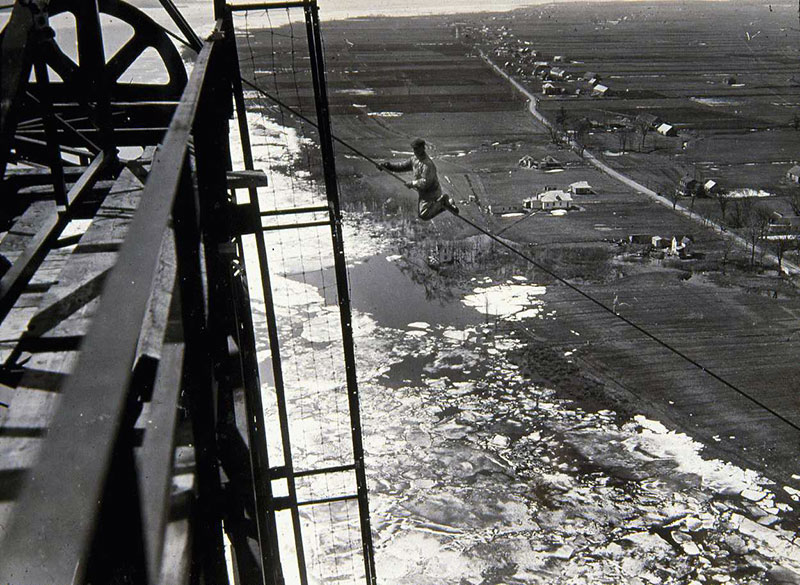 A lineworker doing maintenance at the top of a pylon