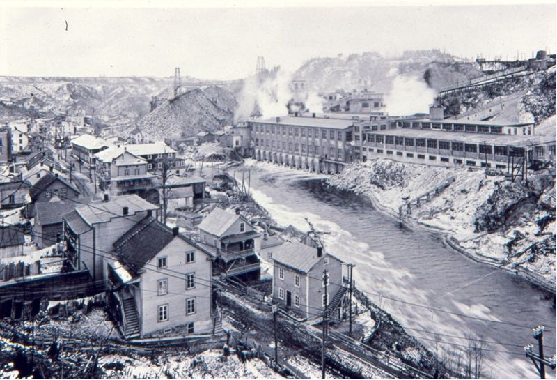 L'usine de papiers Belgo en bordure de la rivière Shawinigan. On aperçoit des maisons d'ouvriers.