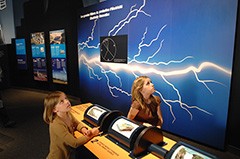 Deux jeunes filles qui visitent l'exposition "Les âges de l'énergie".